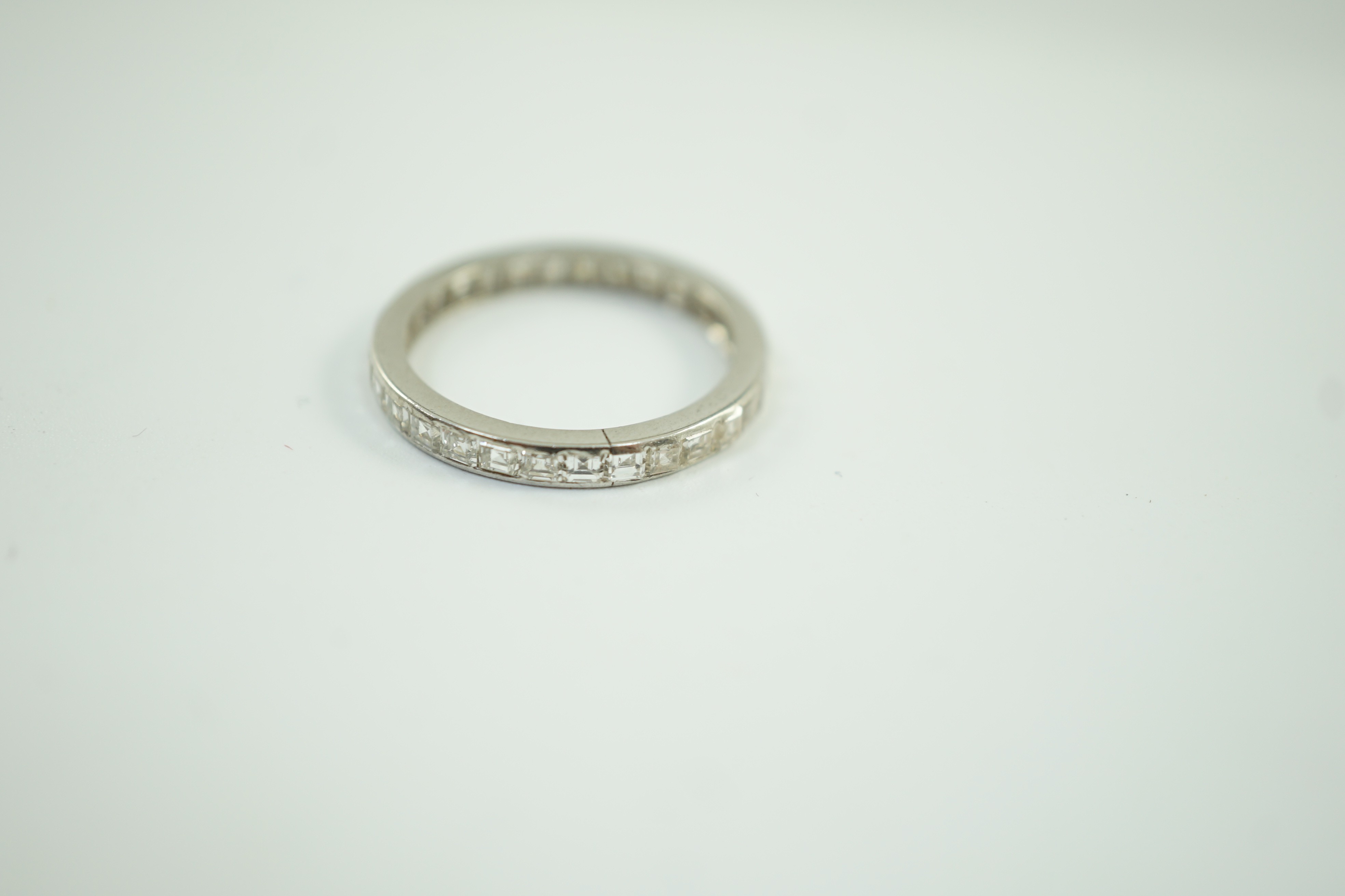 A white metal and square cut diamond set full eternity ring, size M/N, gross weight 2.3 grams.